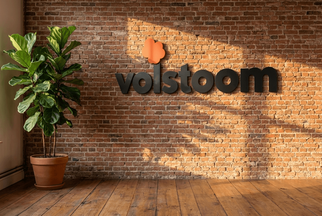 Het Volstoom-logo op een bakstenen muur naast een plant