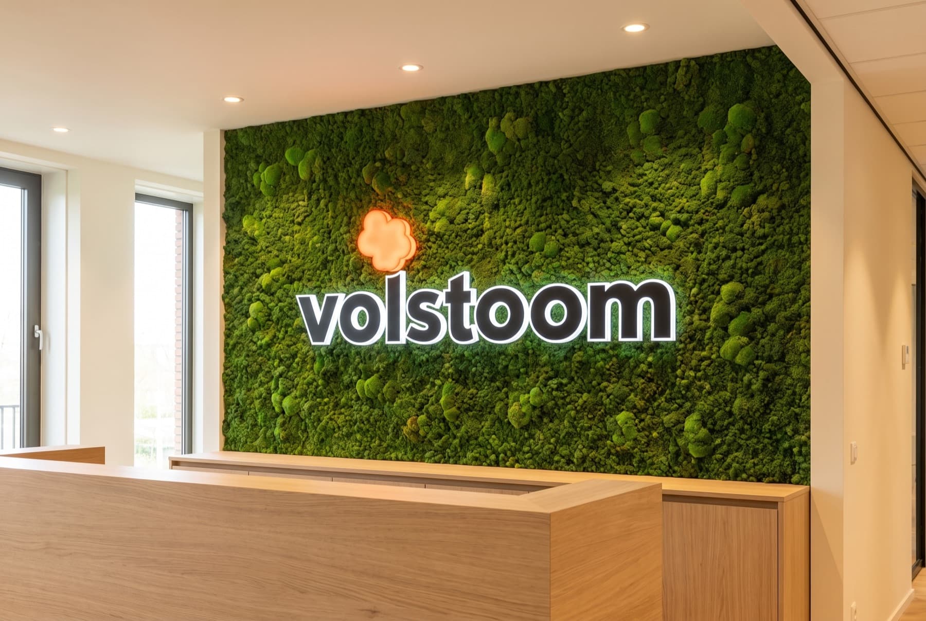 De moswand met het verlichte logo op het kantoor van Volstoom